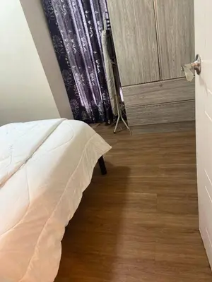 a bedroom with a white bed and a wooden floor at Lumiere Residences in Manila