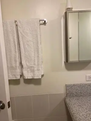 a bathroom with white towels and a mirror at Lumiere Residences in Manila