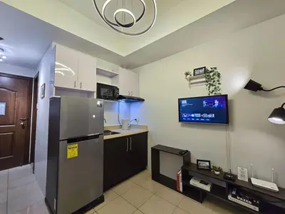 a kitchen with a refrigerator and a tv on the wall at 1BR Condotel Ridgewood Towers Near Airport #RW02-1 in Manila