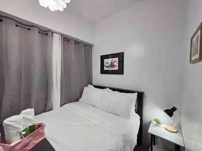 a bedroom with a bed with white sheets and a window at 1BR Condotel Ridgewood Towers Near Airport #RW02-1 in Manila