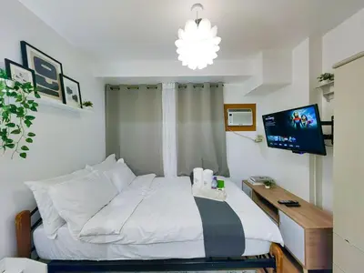 a bedroom with a bed with a desk and a tv at 1BR Condotel Ridgewood Towers Near Airport #RW03-1 in Manila
