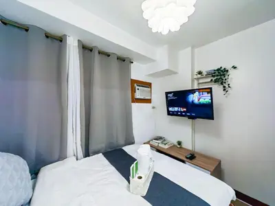 a bedroom with a bed and a tv on the wall at 1BR Condotel Ridgewood Towers Near Airport #RW03-1 in Manila