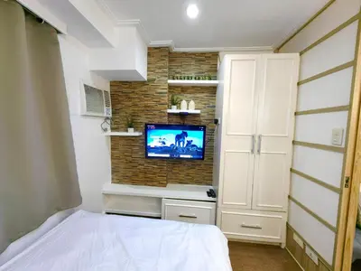 a bedroom with a bed and a tv on a brick wall at 1BR Condotel Ridgewood Towers Near Airport #RW05-1 in Manila