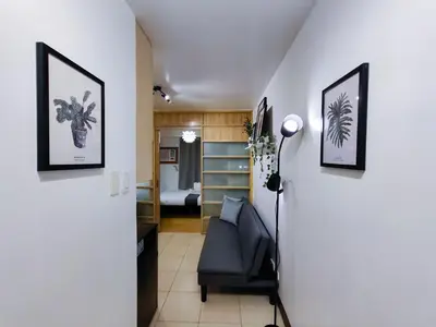 a hallway with a black chair and a bedroom at 1BR Condotel Ridgewood Towers Near Airport #RW04-1 in Manila