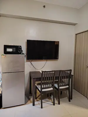 a room with a television and a table and chairs at Zenys Staycation at Shore 1 Residences in Manila
