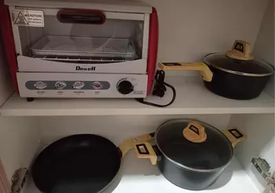a kitchen shelf with a toaster oven and a pot and pans at Relax Condotel in Manila