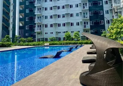 a swimming pool with lounge chairs next to a building at Relax Condotel in Manila