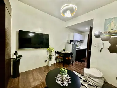 a living room with a large tv on a wall at MyScape at Air Residences Makati in Manila