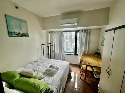 a bedroom with a bed and a desk and a window at MyScape at Air Residences Makati in Manila