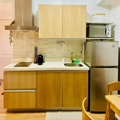 a kitchen with wooden cabinets and a stainless steel refrigerator at Casa Kalma - Beach View Staycation in Manila