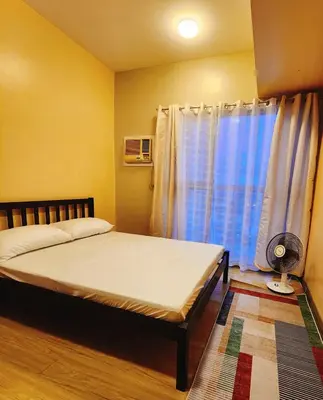 a bedroom with a bed and a window with a fan at 2BR 90sqm Furnished Condo Shaw Blvd, Mandaluyong in Manila