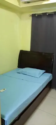 a bed with a wooden headboard in a room at Ladybugs Condotel SR in Manila