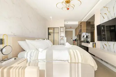 a white bedroom with a large bed and a kitchen at Hotel Like Staycation Near Airport and MOA Porongs Oasis in Manila