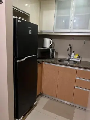 a kitchen with a black refrigerator and a microwave at L&D Condominium in Manila