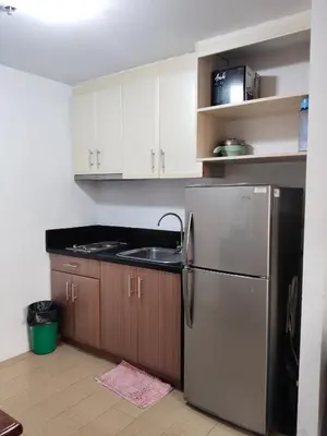 a kitchen with a stainless steel refrigerator and wooden cabinets at Rose150newportpasay in Manila