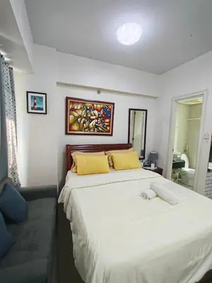 a bedroom with a large white bed with yellow pillows at Rose150newportcondopasay in Manila