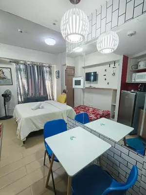 a room with a bed and two tables and chairs at Rose150newportcondopasay in Manila