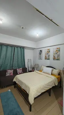 a bedroom with a large bed and a couch at JennieRose150newportpasay in Manila