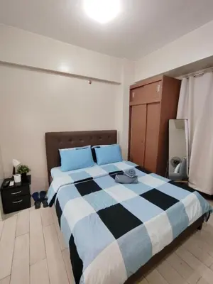 a bedroom with a large bed with blue pillows at JennieRosecondo150newportpasay in Manila