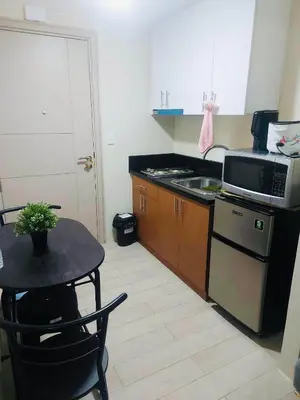 a small kitchen with a table and a microwave at JennieRosecondo150newportpasay in Manila