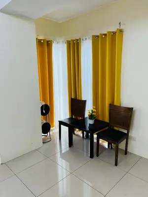 a dining room with yellow curtains and a table and chairs at Unit 958 B Shell Residences 2br in Manila