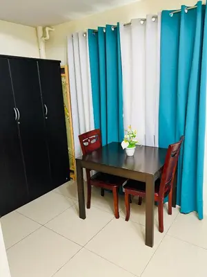 a dining room with a table and chairs and blue curtains at Unit 958 B Shell Residences 2br in Manila