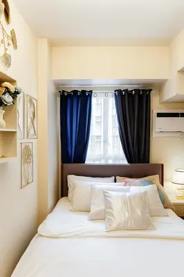 a bedroom with a large bed with blue curtains at Manila Stay near Manila Airport NAIA Mall Fast Wifi Kitchenette Rouzelea Nest in Manila