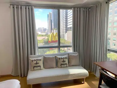 a living room with a couch in front of a large window at Avant at the Fort 360 City Center views in BGC Taguig w Pool Access in Manila