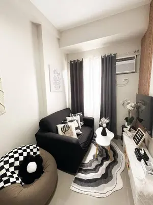a living room with a black couch and a table at Nap & Go Staycation in Manila