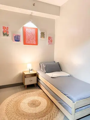 a bedroom with a bed and a nightstand with a rug at Nap & Go Staycation in Manila