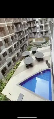 a large apartment building with a swimming pool and umbrellas at S Residences MOA complex in Manila