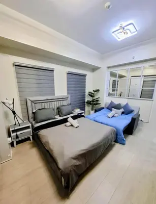 a bedroom with two beds with blue sheets and windows at Gallardo Condo Stays at Eighty One Newport Boulevard Newport City, Pasay City near NAIA Terminal 3 in Manila
