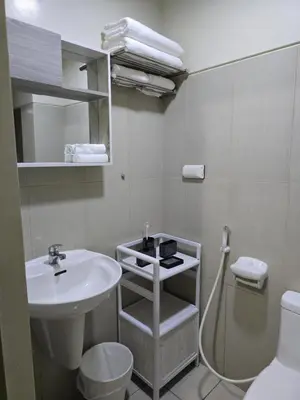 a white bathroom with a sink and a toilet at Rhoydez Condotel Breeze Residence in Manila