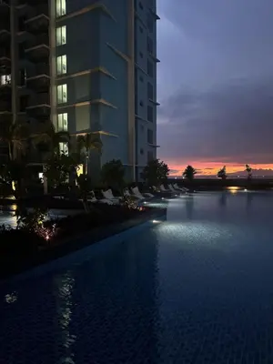 a swimming pool in front of a building at sunset at Panoramic Landscape Seaview, 2BR, near Airport, 11m in Manila