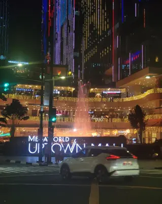 a car driving down a city street at night at Stylish 1br inside BGC at Uptown Parksuites - 24k in Manila