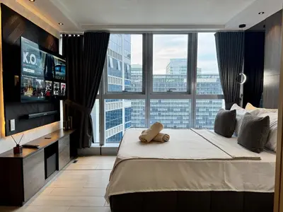 a bedroom with a large bed and a large window at Stylish 1br inside BGC at Uptown Parksuites - 24k in Manila