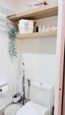 a bathroom with a toilet and a shelf with towels at Student Hub at DLSU in Pasong Bayog