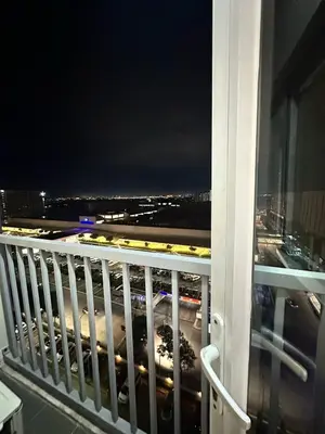 a balcony with a view of a city at night at Cozy Condo at South Residences in Manila