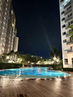 a swimming pool at night with two tall buildings at Cozy Condo at South Residences in Manila
