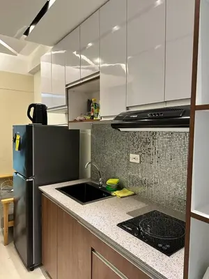 a kitchen with a sink and a refrigerator at Cozy Condo at South Residences in Manila