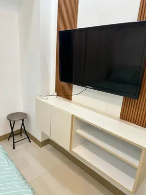 a flat screen tv sitting on top of a white cabinet at Cozy Condo at South Residences in Manila