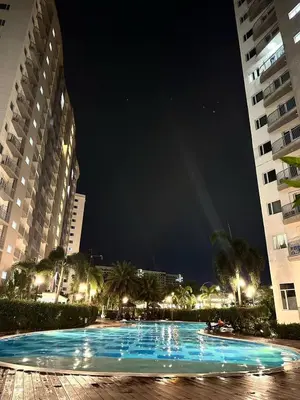 a large swimming pool at night with two buildings at Cozy Condo at South Residences in Manila