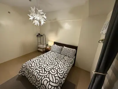 a bedroom with a black and white bed and a chandelier at HAVEN on the 28th in Manila