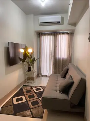 a living room with a couch in front of a window at comfy 1 bedroom family condo in Manila