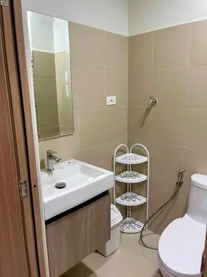 a bathroom with a sink and a toilet and a mirror at comfy 1 bedroom family condo in Manila