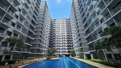 a large apartment building with a swimming pool in front of it at comfy 1 bedroom family condo in Manila