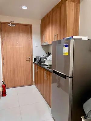 a kitchen with a stainless steel refrigerator and wooden cabinets at comfy 1 bedroom family condo in Manila