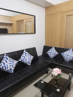 a black couch with blue and white pillows in a living room at Shell Residences Family Suites 2 in Manila