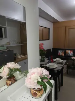 a kitchen and living room with a table and flowers at Shell Residences Family Suites 2 in Manila