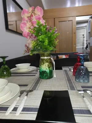 a table with a vase with pink flowers in it at Shell Residences Family Suites 2 in Manila